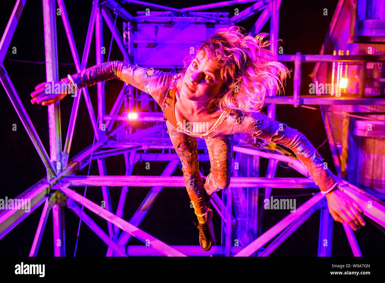 Aerial performer Rachel Fox hangs in the air from a mining pit headframe during the theatrical performance of Estah???s Story, which is set in the old mine workings at Heartlands World Heritage Site, Cornwall, featuring aerial performances, song and spoken word, retelling stories from the Cornish mining industry in the 1800s. Stock Photo