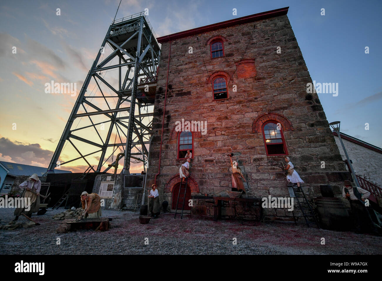 Performers climb up to the windows during the theatrical performance of Estah???s Story, which is set in the old mine workings at Heartlands World Heritage Site, Cornwall, featuring aerial performances, song and spoken word, retelling stories from the Cornish mining industry in the 1800s. Stock Photo