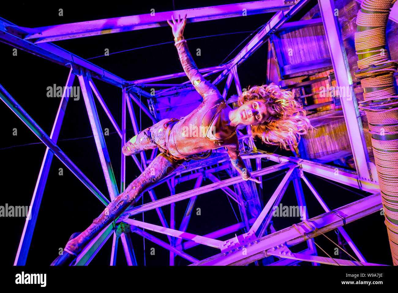 Aerial performer Rachel Fox hangs in the air from a mining pit headframe during the theatrical performance of Estah???s Story, which is set in the old mine workings at Heartlands World Heritage Site, Cornwall, featuring aerial performances, song and spoken word, retelling stories from the Cornish mining industry in the 1800s. Stock Photo