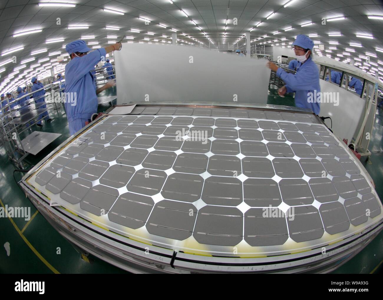 --FILE-- Chinese factory workers manufacture solar power panels at a plant in Nantong, east Chinas Jiangsu province, January 5, 2010. The focus of Stock Photo