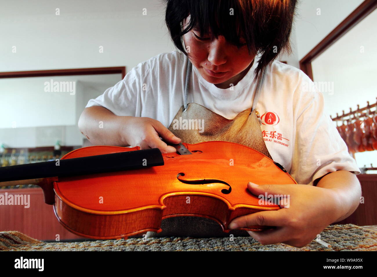 A Chinese worker makes a violin in the factory of Beijing Huadong