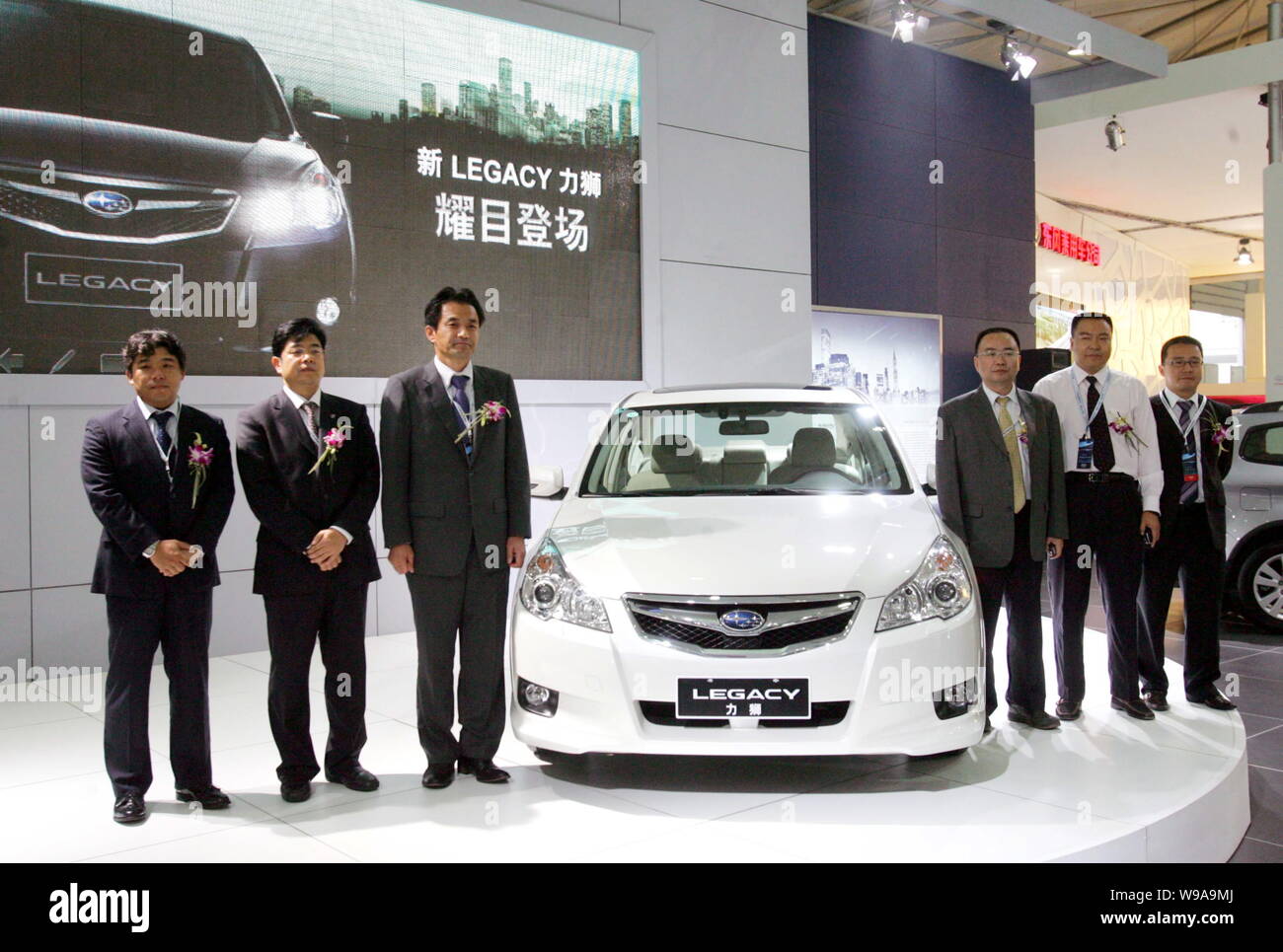 --FILE-- Unnamed executives from Subaru and guests pose next to a Subaru Legacy during an auto show in Chengdu, southwest Chinas Sichuan province, Sep Stock Photo