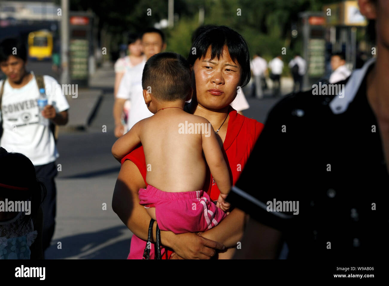 A Chinese woman holding her half-naked kid walks under scorching sunshine  in sweltering weather in Beijing, China, July 5, 2010. A searing heat wave  Stock Photo - Alamy