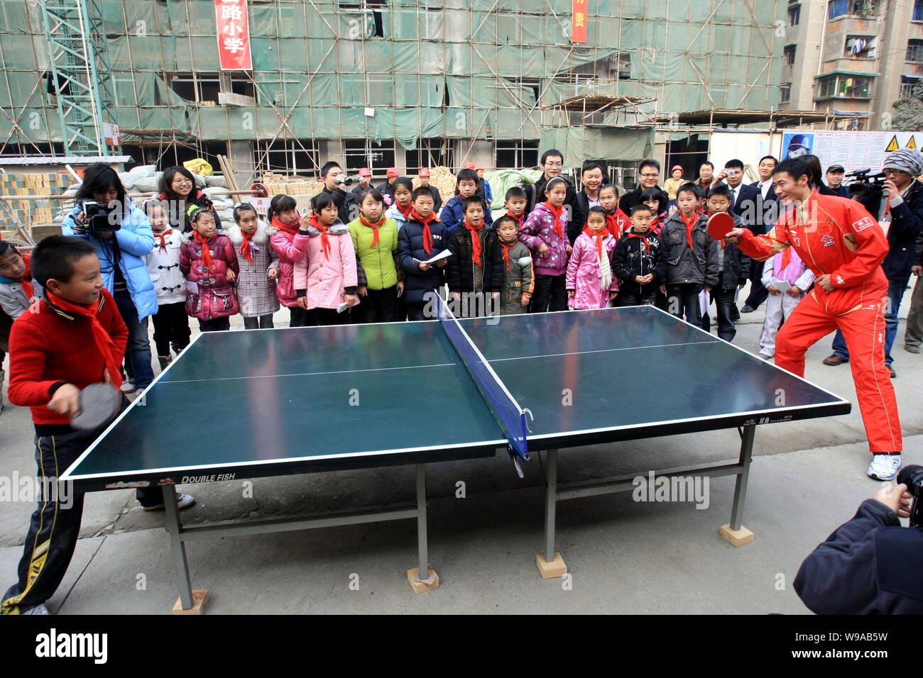 Chinese table tennis player Wang Liqin, right, plays table tennis with a student during a visit