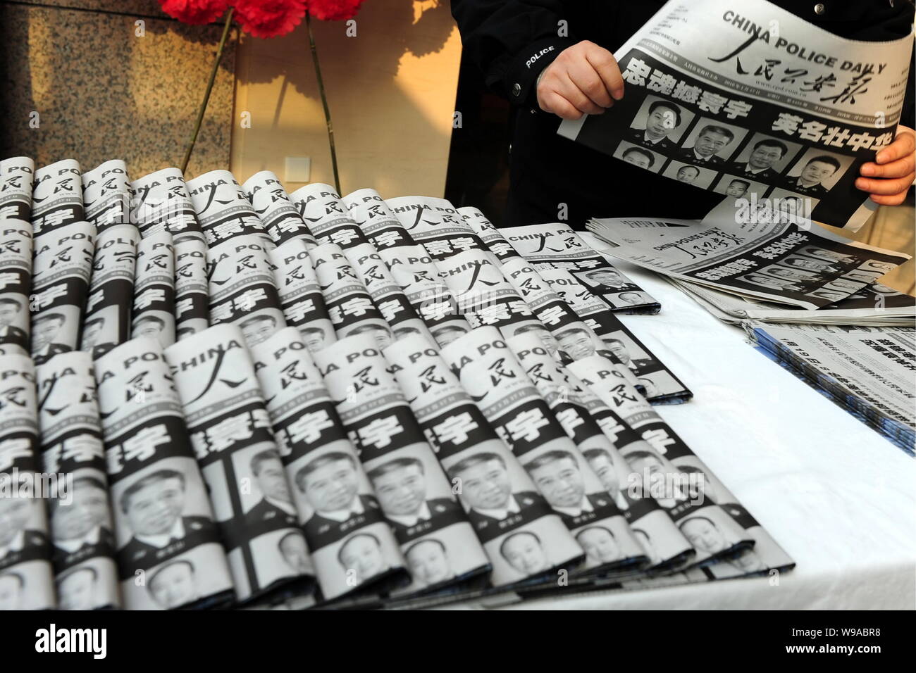 A Chinese police officer distributes newspapers with portraits of the eight police officers who died in the Haiti earthquake during a mourning ceremon Stock Photo