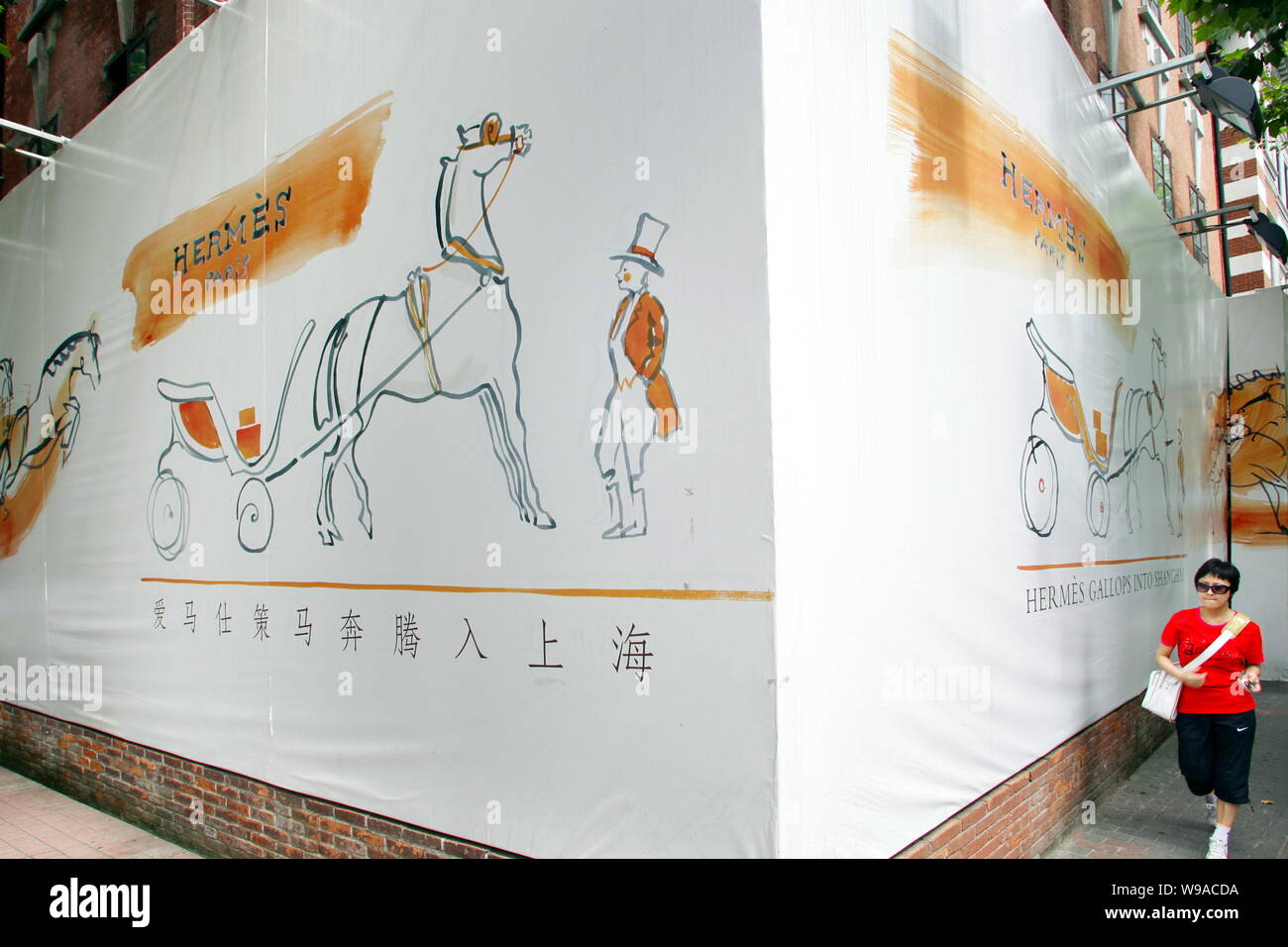 A Chinese Woman Walks Past An Advertisement For Hermes - 