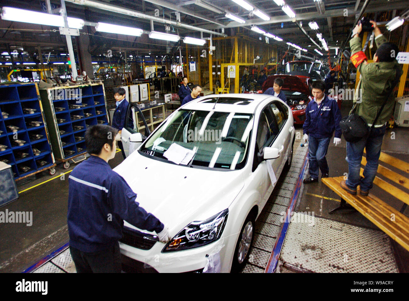Chinese factory workers assemble Ford Focus cars on the assembly line ...