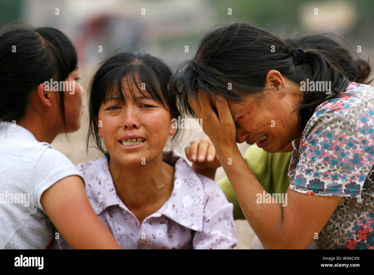 Chinese women weep over the death of their family members killed in the devastating landslide in
