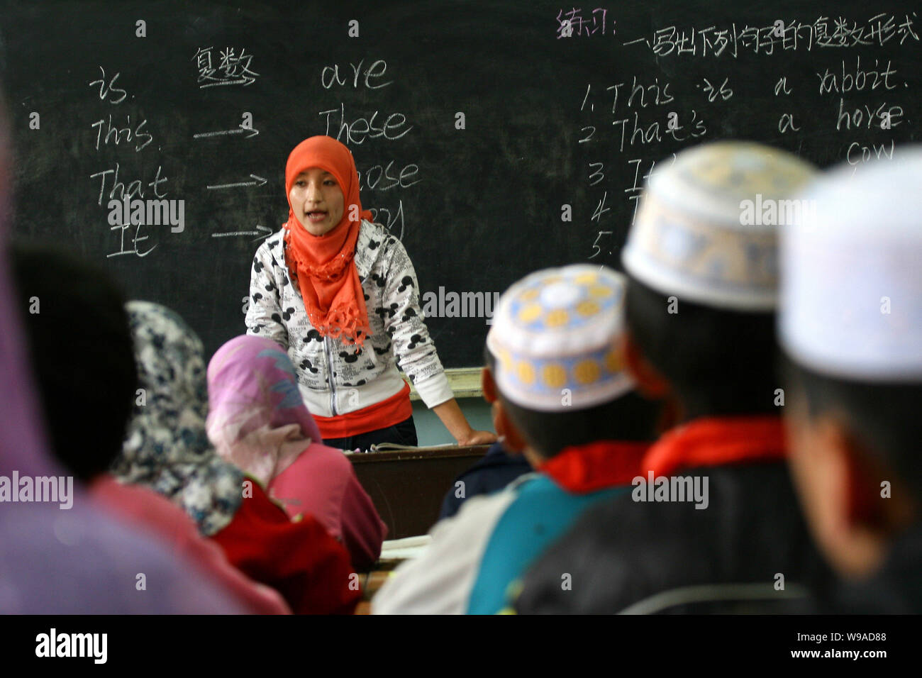 A Hui ethnic teacher teaches students English during a lesson at the Heping Primary School in Linxia, northwest Chinas Gansu province, June 30, 2010. Stock Photo
