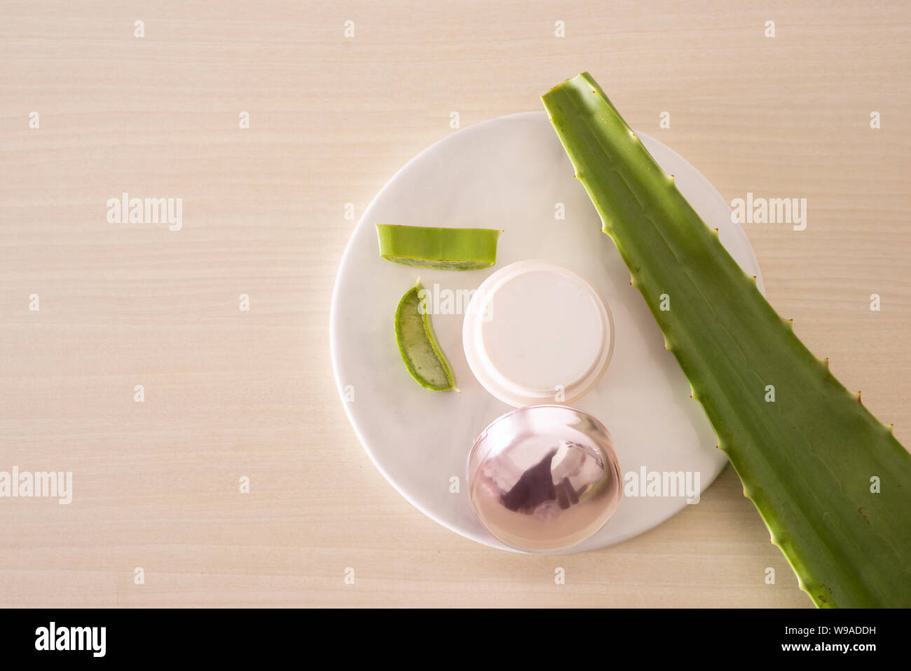 Jar of cream with alo leave and chopped aloe on marble round board Stock Photo