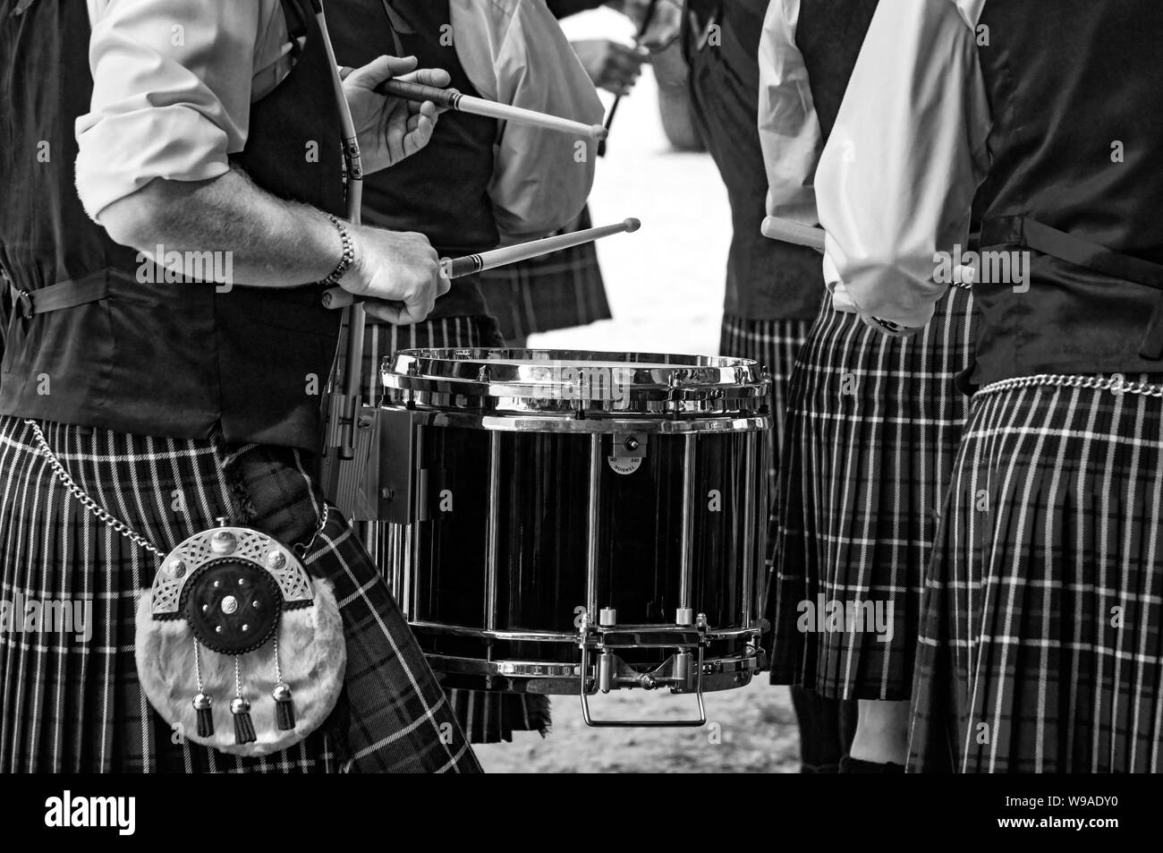Closeup of the traditional Scottish drum and the hands of a drummer wearing kilt in Scottish band playing outdoors. Stock Photo