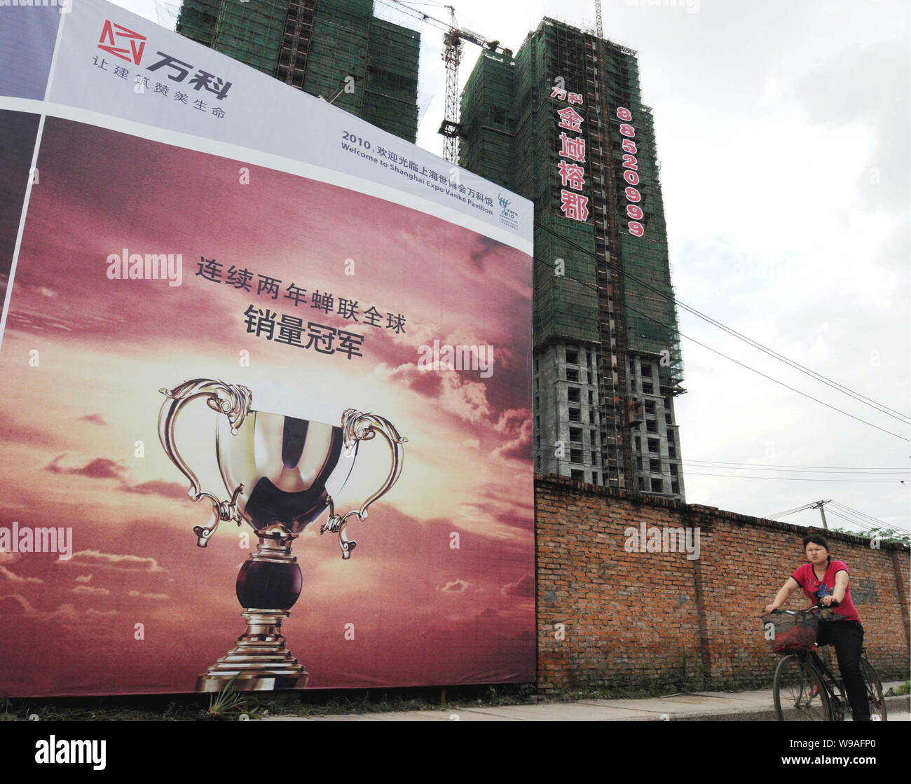 A Chinese Woman Rides Her Bicycle Past An Under Construction