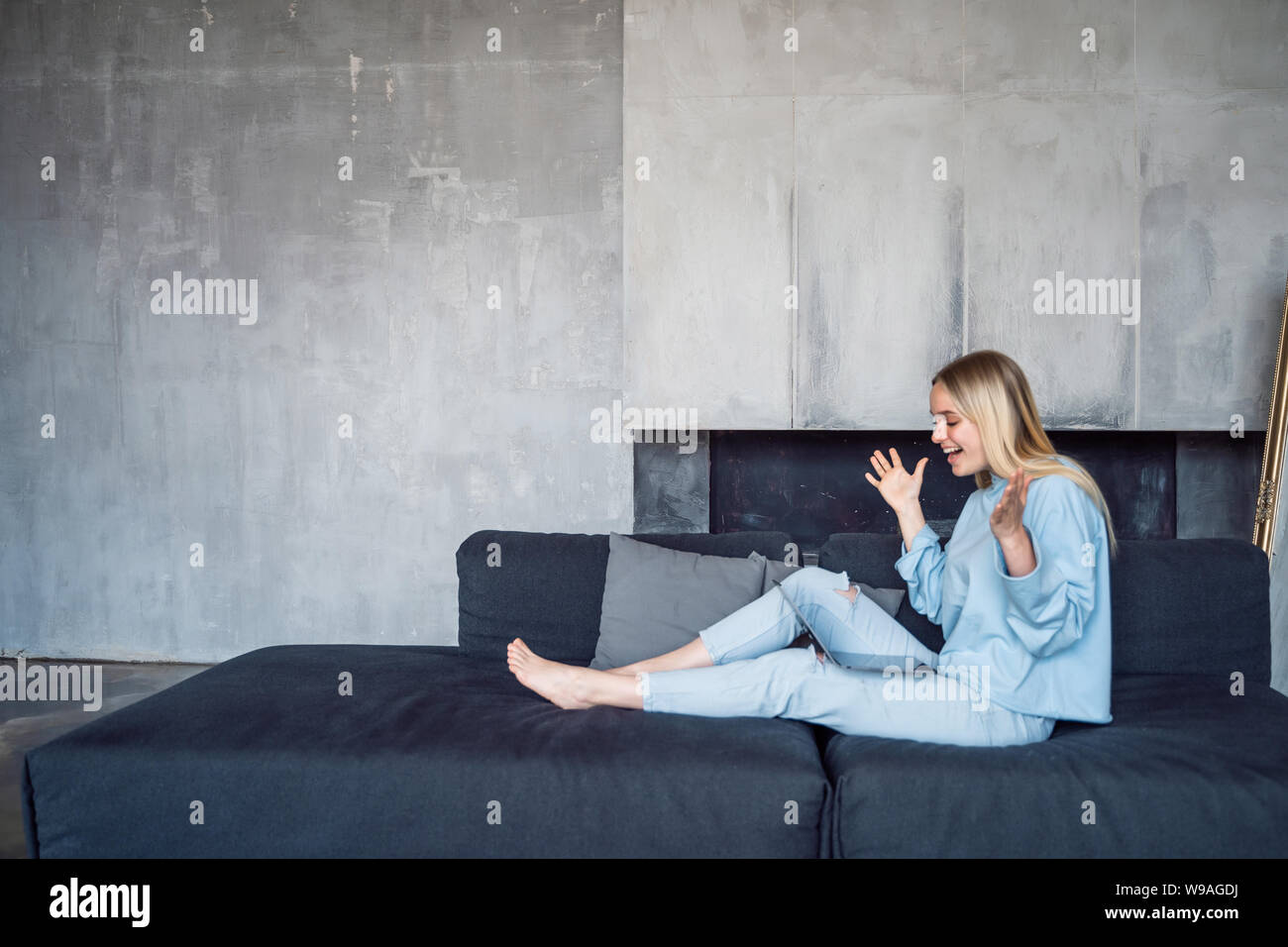 Image of happy woman using silver laptop while sitting on sofa Stock ...