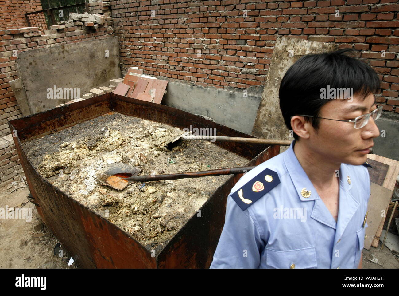 A Chinese law enforcement officer stands in front of a cart of kitchen