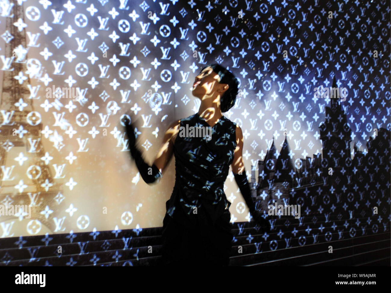 A model stands in front of a wall on which Louis Vuitton logos are  projected during an exhibition inside the French Pavilion in the Expo site  in Shang Stock Photo - Alamy
