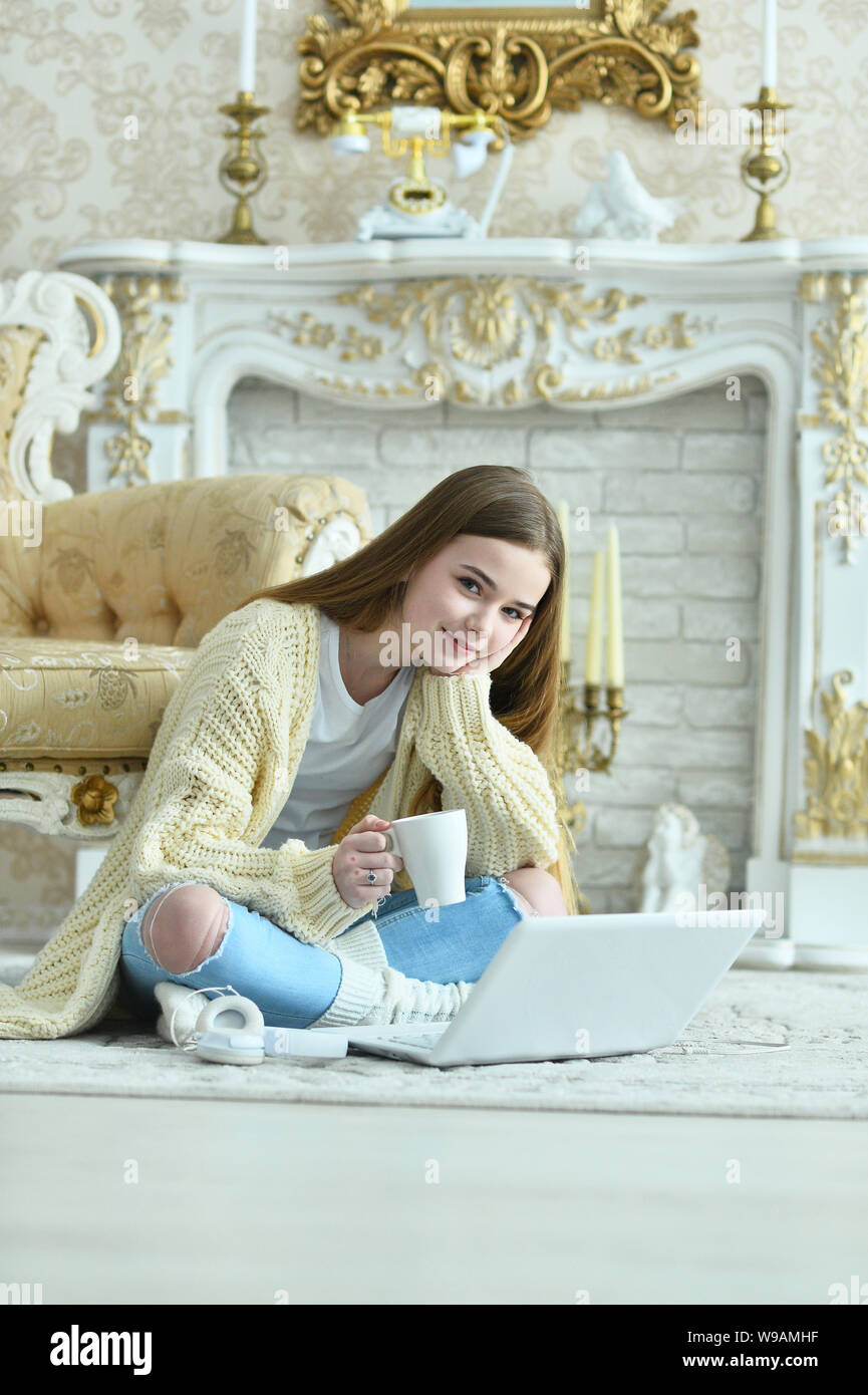 Portrait of beautiful teen girl sitting on floor near vintage armchair ...