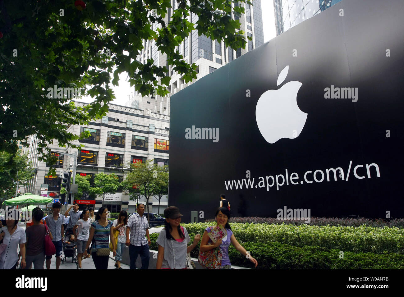 Local Chinese residents walk past a billboard of Apple at the Hong Kong Plaza on Huaihai Road in Shanghai, China, 13 September 2010.   Apple is prepar Stock Photo
