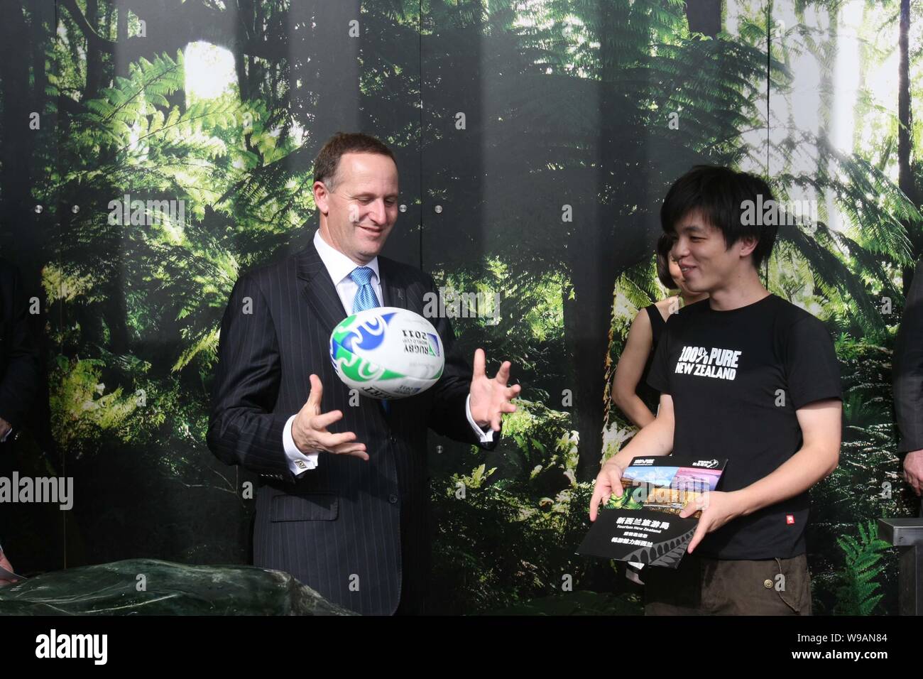 New Zealand Prime Minister John Key presents a rugby ball to a Chinese visitor at the New Zealand Pavilion in the World Expo Park in Shanghai, China, Stock Photo