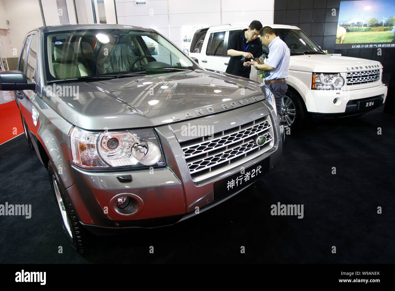 --FILE--A Chinese car buyer talks with a salesman between Land Rover Discovery 4 and Freelander 2 in a dealership in Shanghai, China, 11 June 2010. Stock Photo