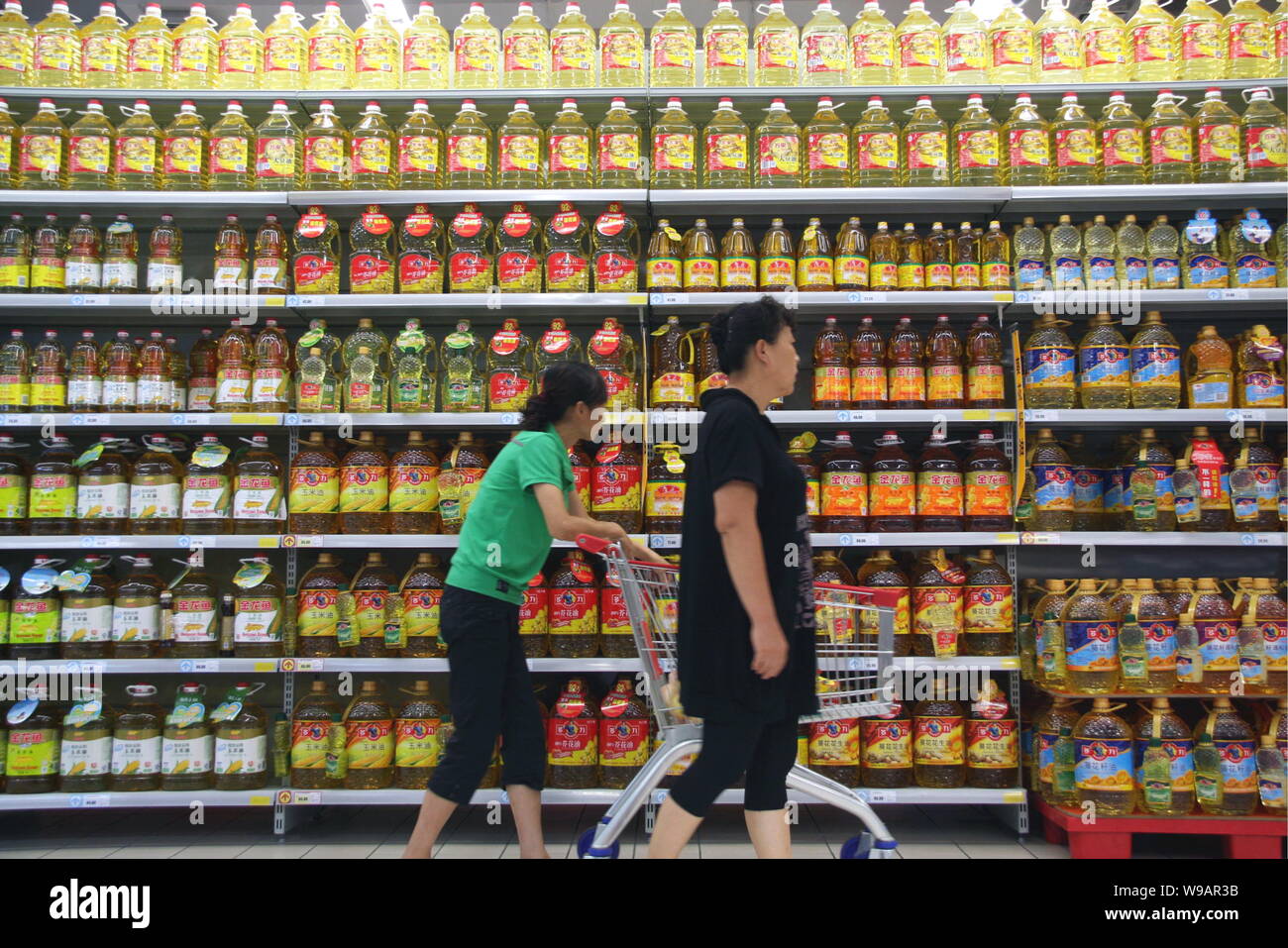 Chinese consumers walk past bottles of cooking oil at a supermarket in Nantong, east Chinas Jiangsu Privince, September 9, 2010.   China brought forwa Stock Photo