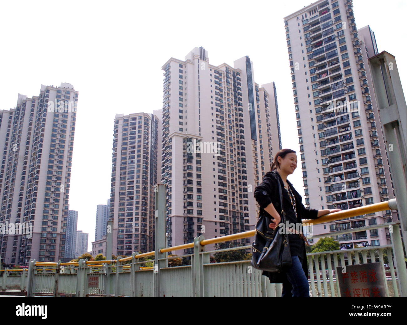 --FILE--A Chinese woman walks past a cluster of high residential apartment buildings in Shanghai, China, 17 April 2010.   The Shanghai government has Stock Photo