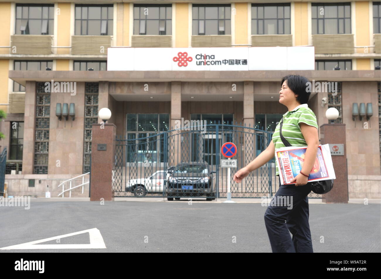 A Chinese woman walks past the headquarters of China Unicom in Beijing, China, August 2, 2010.   As if Apple does not have enough problems with iPhone Stock Photo