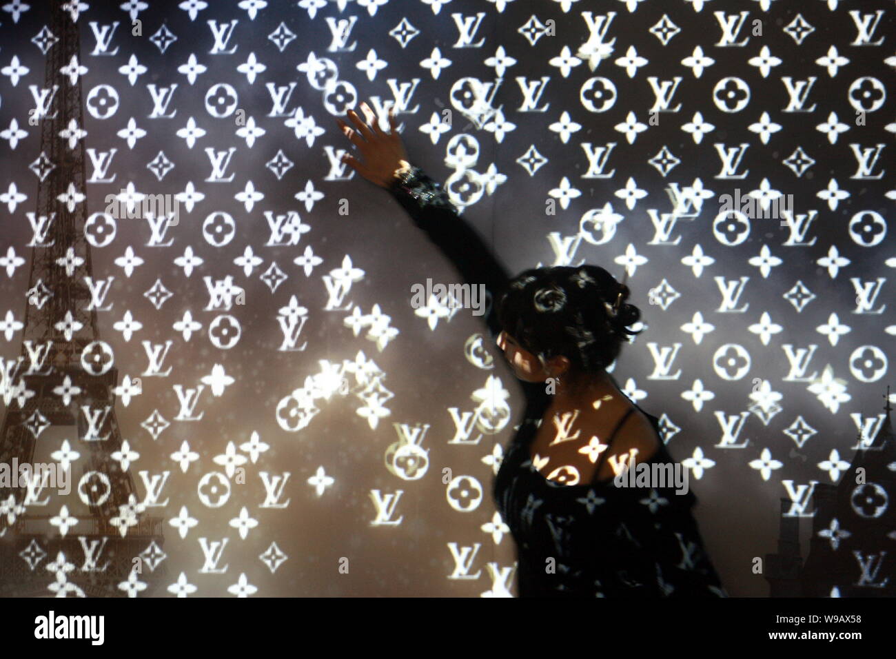 A model stands in front of a wall on which Louis Vuitton logos are  projected during an exhibition inside the French Pavilion in the Expo site  in Shang Stock Photo - Alamy