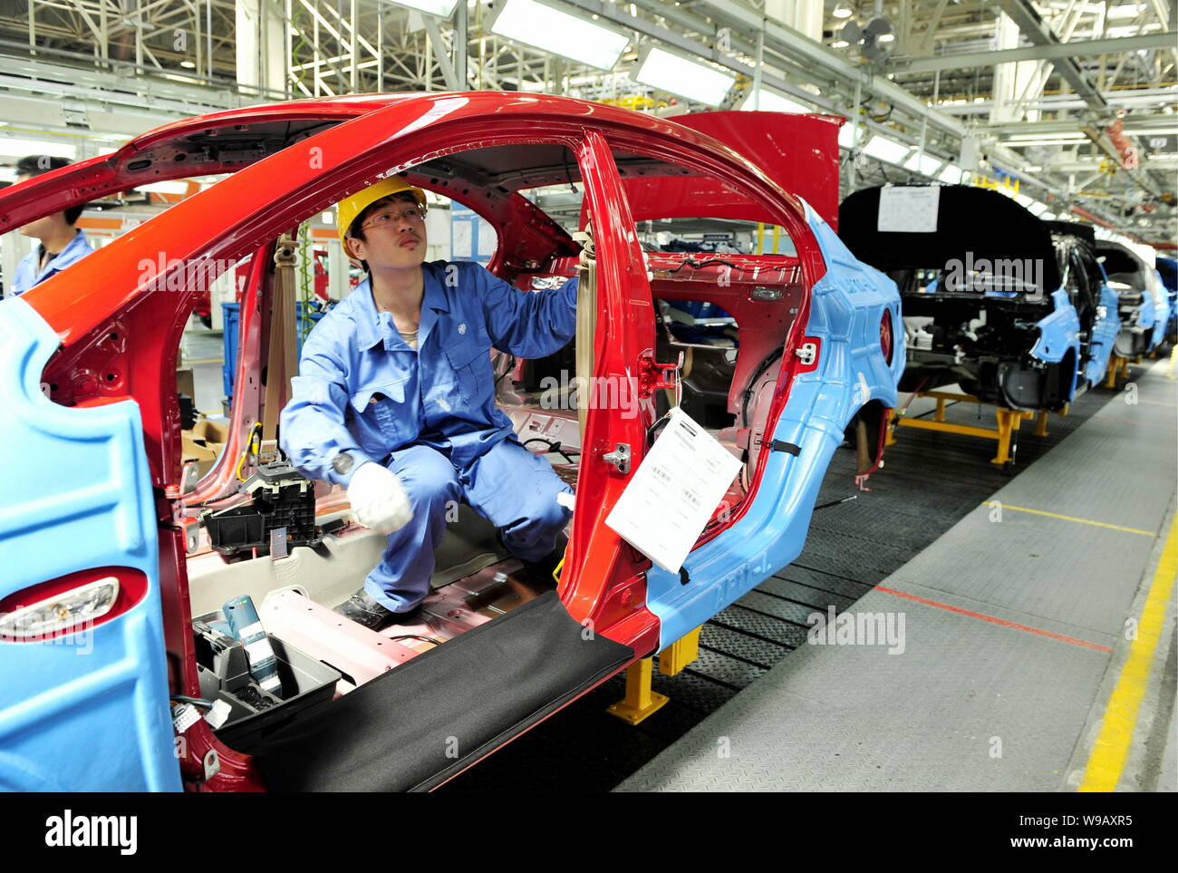 A Chinese factory worker assembles a Roewe 350 car on the assembly line ...