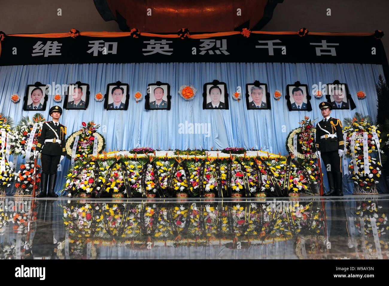 Two Chinese paramilitary policemen stand guard in front of portraits of the eight police officers who died in the Haiti earthquake during a mourning c Stock Photo