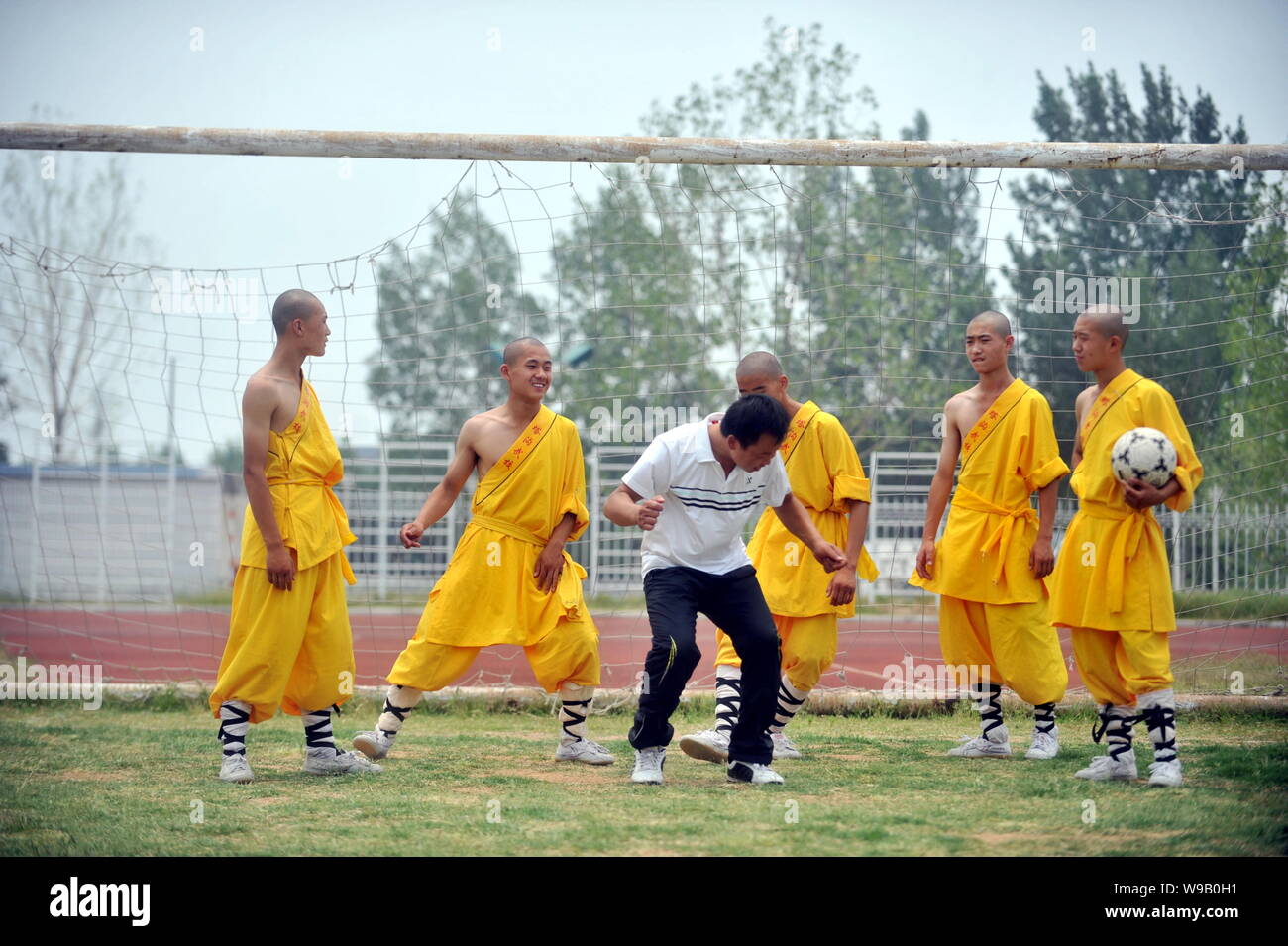A coach shows football techniques to young Chinese monks from Shaolin Temple Tagou Wushu School during a training session in Zhengzhou, central Chinas Stock Photo