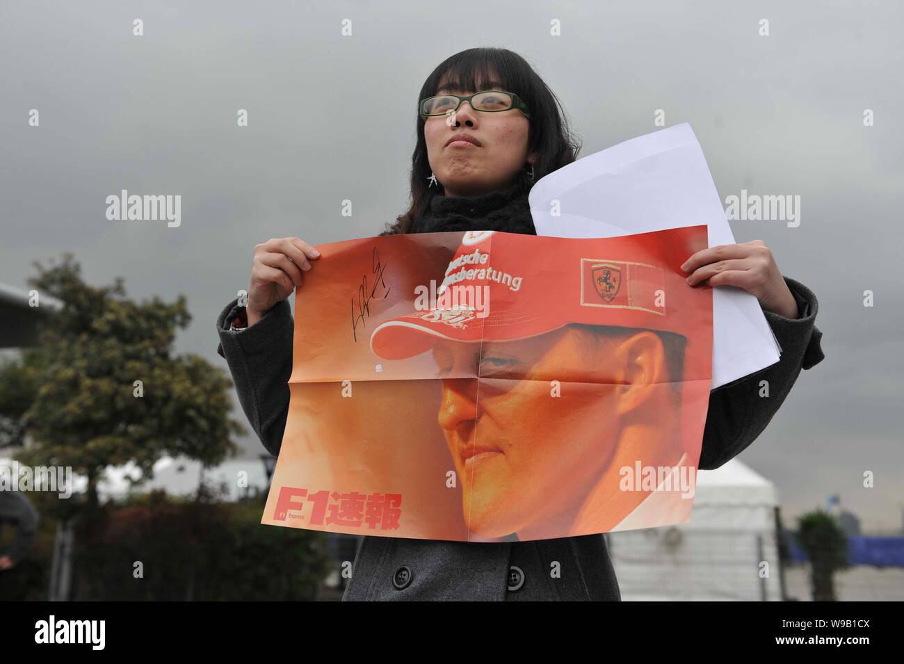 A Chinese girl holds a poster of German F1 driver Michael Schumacher of Mercedes GP team to show her support at the Shanghai International Circuit in Stock Photo