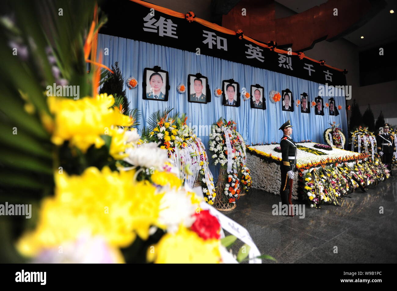 Two Chinese paramilitary policemen stand guard in front of portraits of the eight police officers who died in the Haiti earthquake during a mourning c Stock Photo