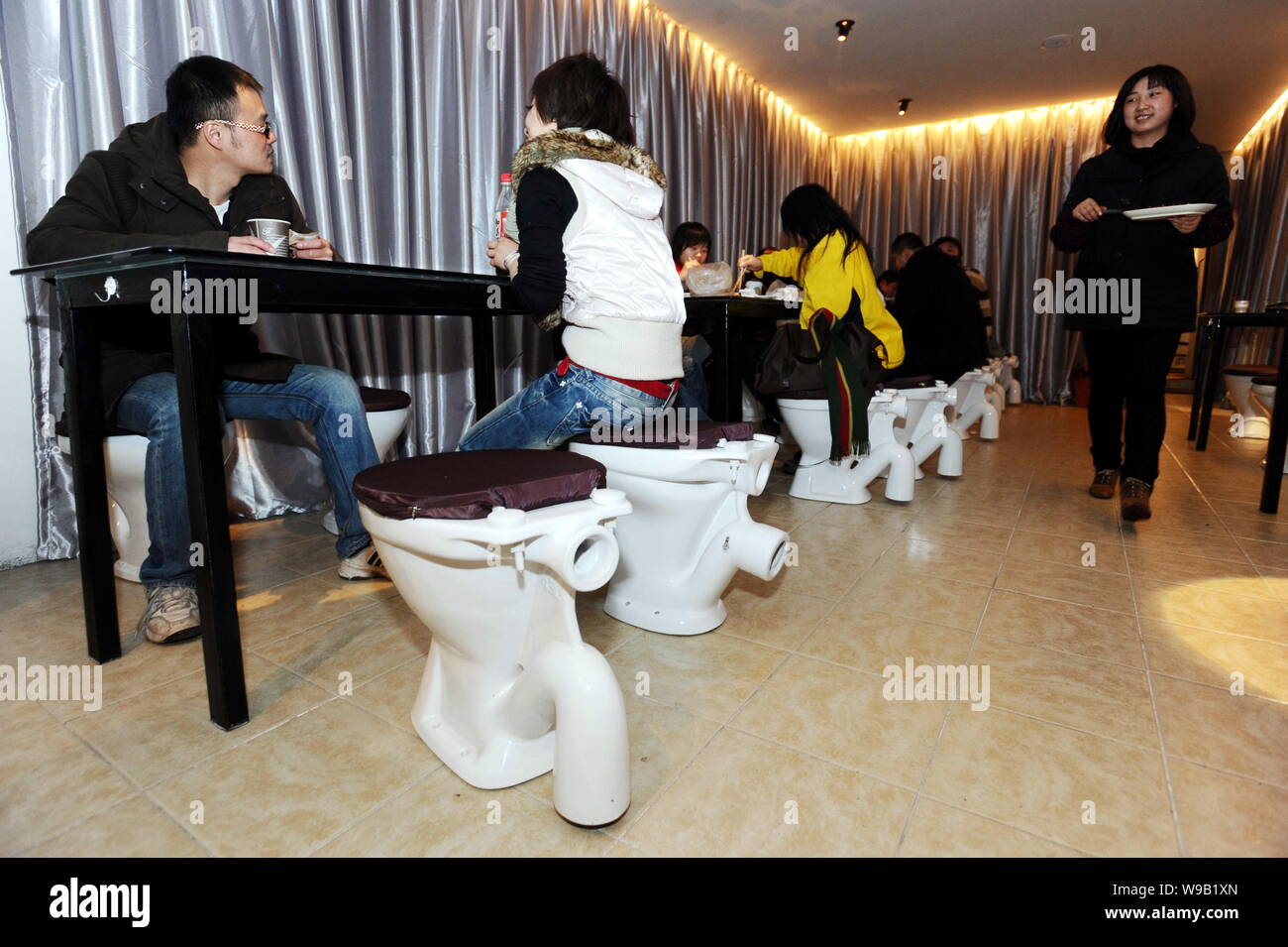 Chinese customers sitting on toilets eat barbecue at a toiletthemed