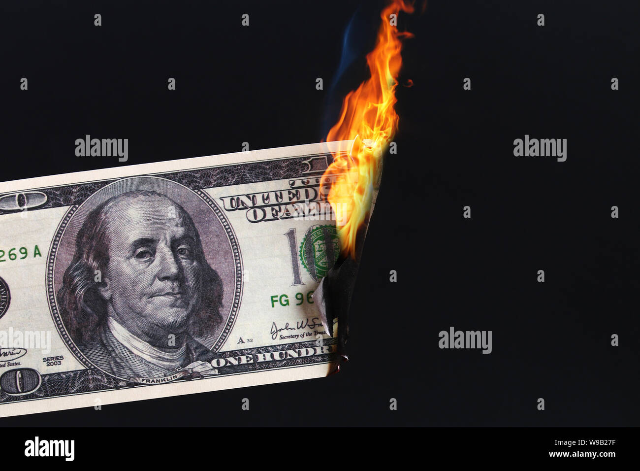one hundred American dollar burning in fire flame on black paper background, close-up of bad money. The collapse of the dollar. Devaluation. Falling c Stock Photo