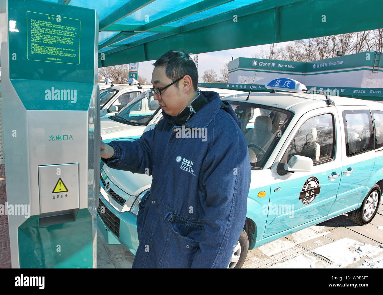 A Chinese worker recharges an electric taxi at an EV charging station in Beijing, China, 30 December 2010.   Beijing will build both fast charging and Stock Photo