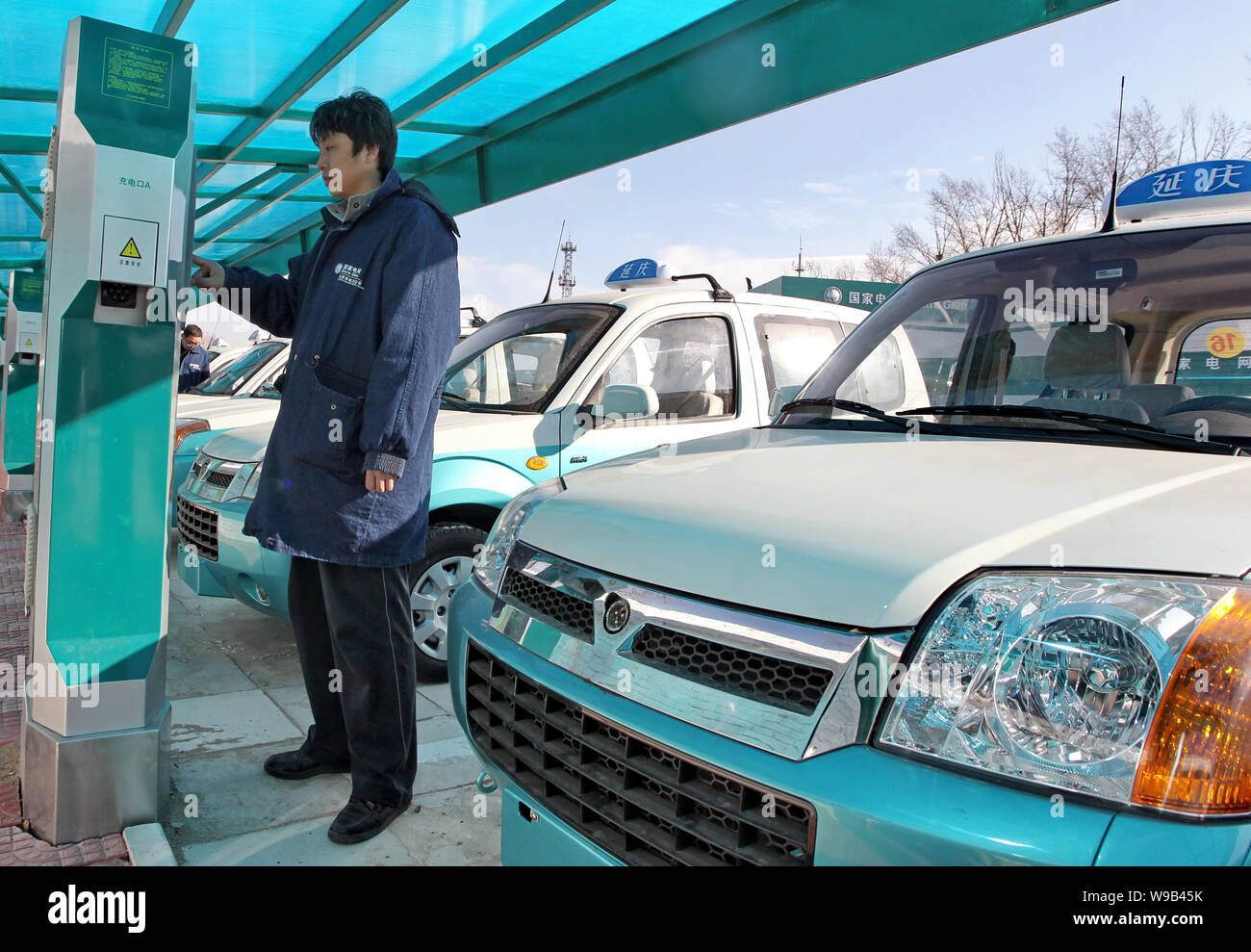 A Chinese worker recharges an electric taxi at an EV charging station in Beijing, China, 30 December 2010.   Beijing will build both fast charging and Stock Photo