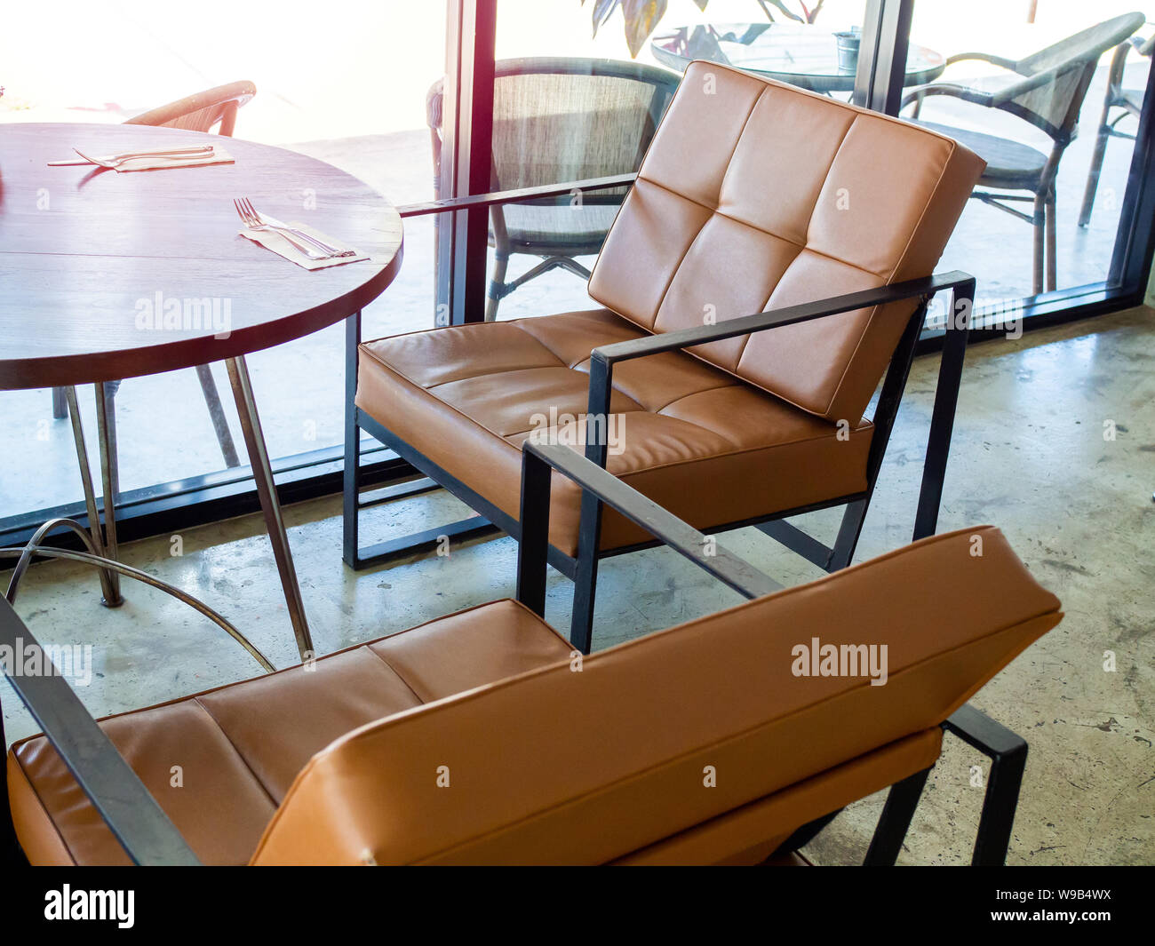 Black Metal Frame And Tan Leather Armchair Retro Style And Round Wooden Table Near Glass Wall In Cafe Stock Photo Alamy
