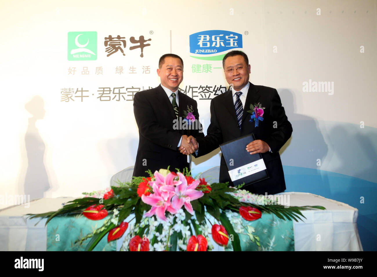 Yang Wenjun, left, President of Mengniu Group, shakes hands with Wei Lihua, Chairman of Junlebao