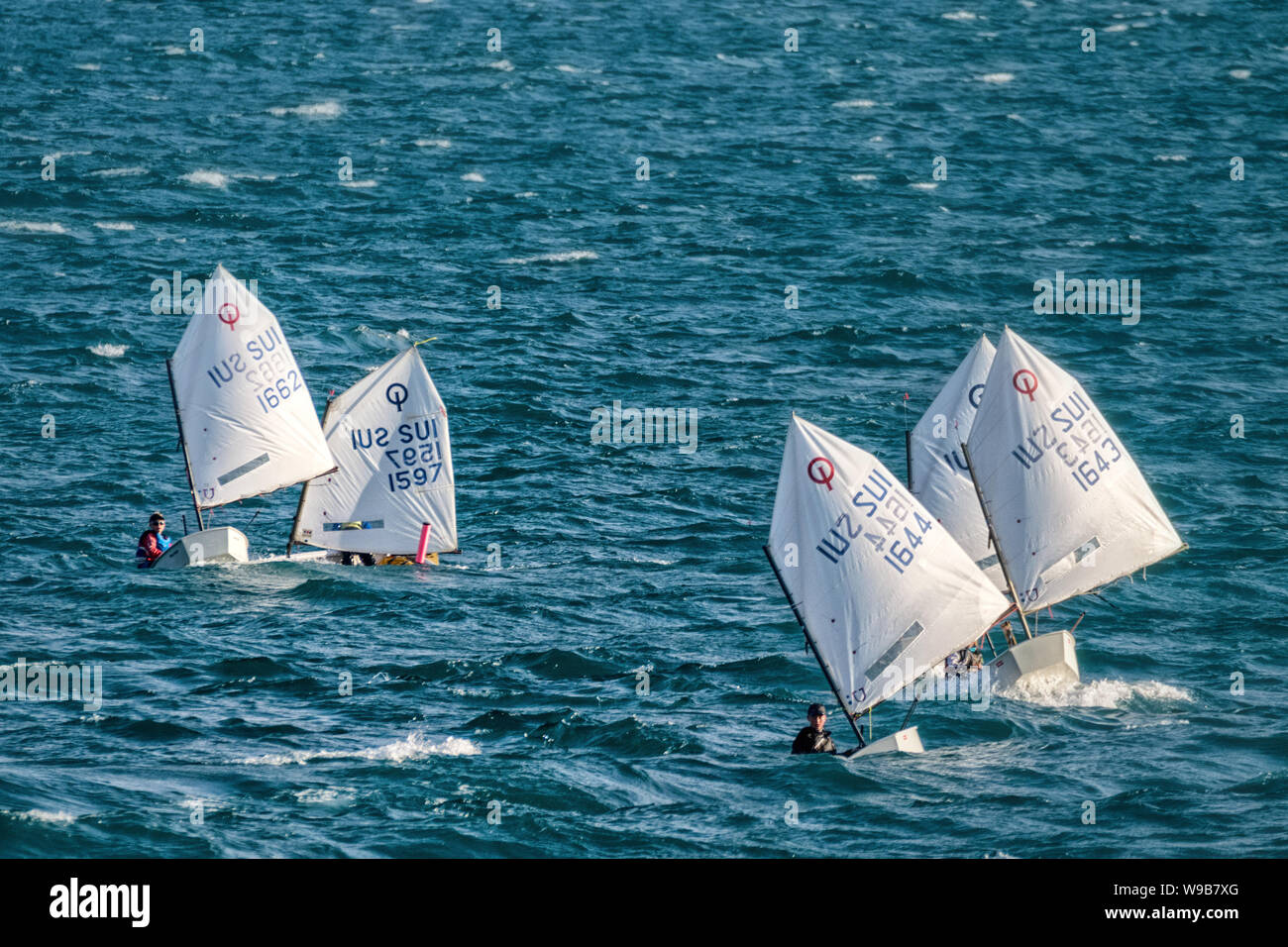 Children sailing Optimist dinghies in big waves Stock Photo