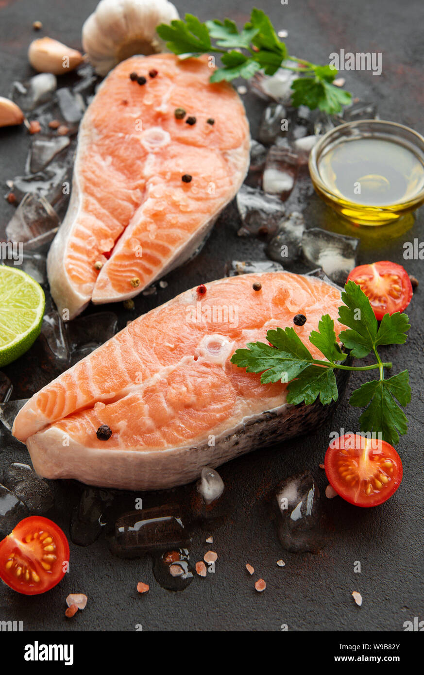 Raw salmon steaks and ingredients on a black slate board Stock Photo ...