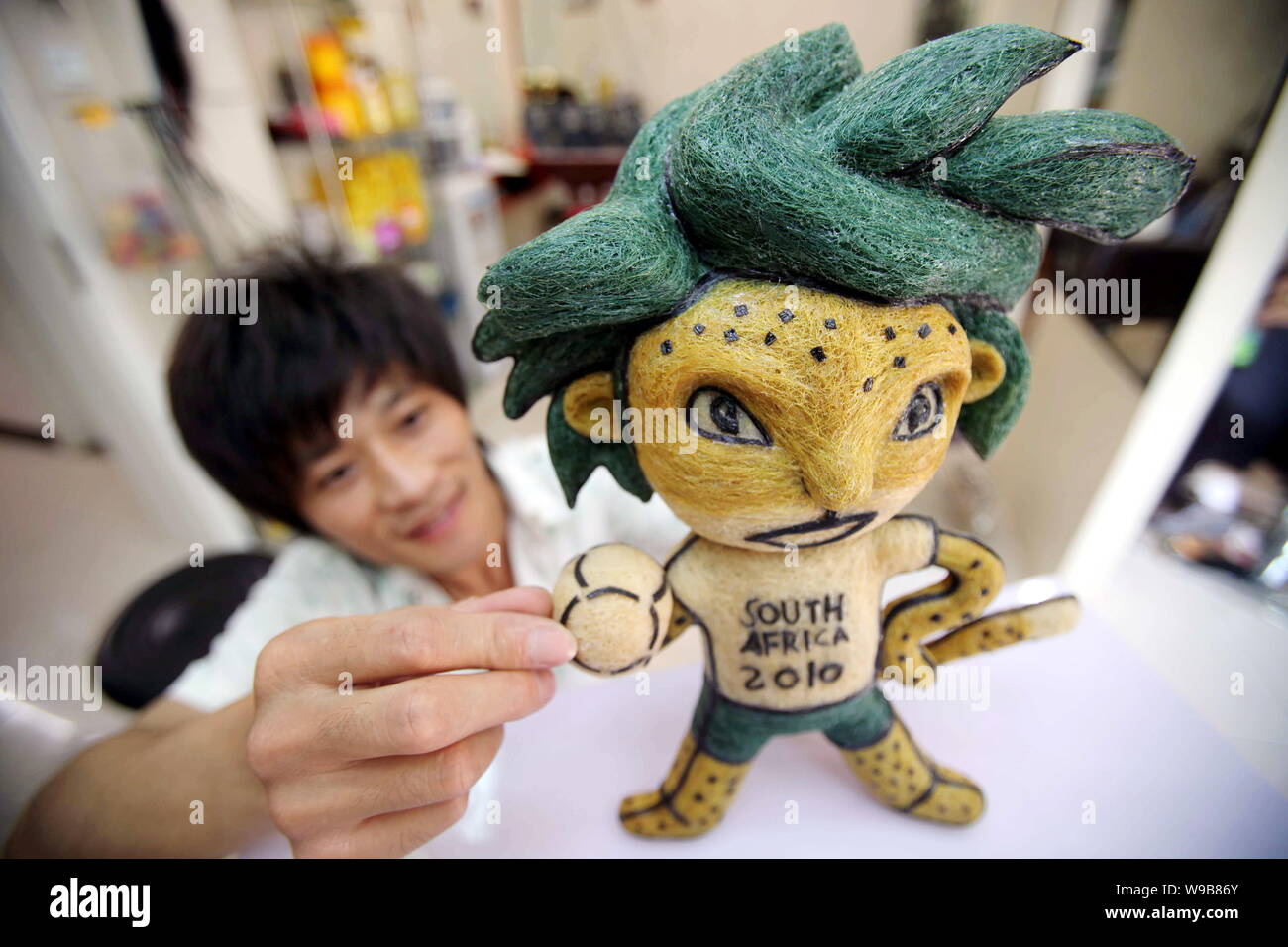 Chinese hairstylist Huang Xin puts final touches on his hair-made Zakumi, the official mascot of the World Cup South Africa 2010, in a hair salon in B Stock Photo