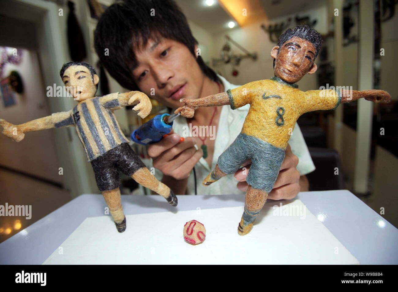Chinese hairstylist Huang Xin puts final touches on two hair-made football players in a hair salon in Beijing, China, 10 June 2010.   Huang is a hair- Stock Photo
