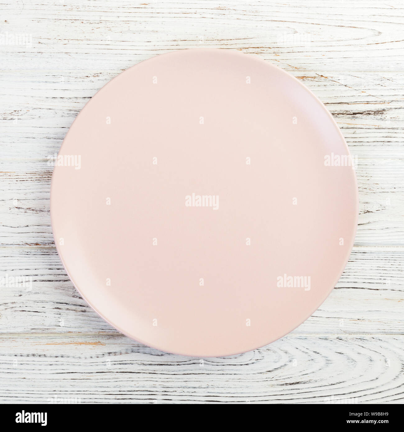 Empty pink or coral round plate on wooden table background. Top view ...