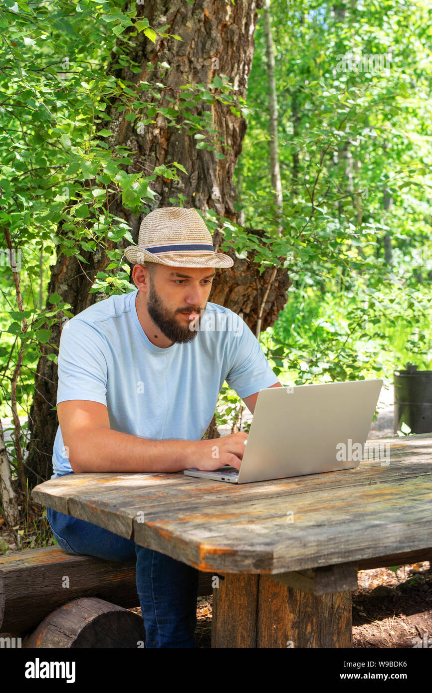 Bearded hipster man working freelance. A freelance computer programmer. Freelance professional work off site on laptop computer outdoor. Stock Photo