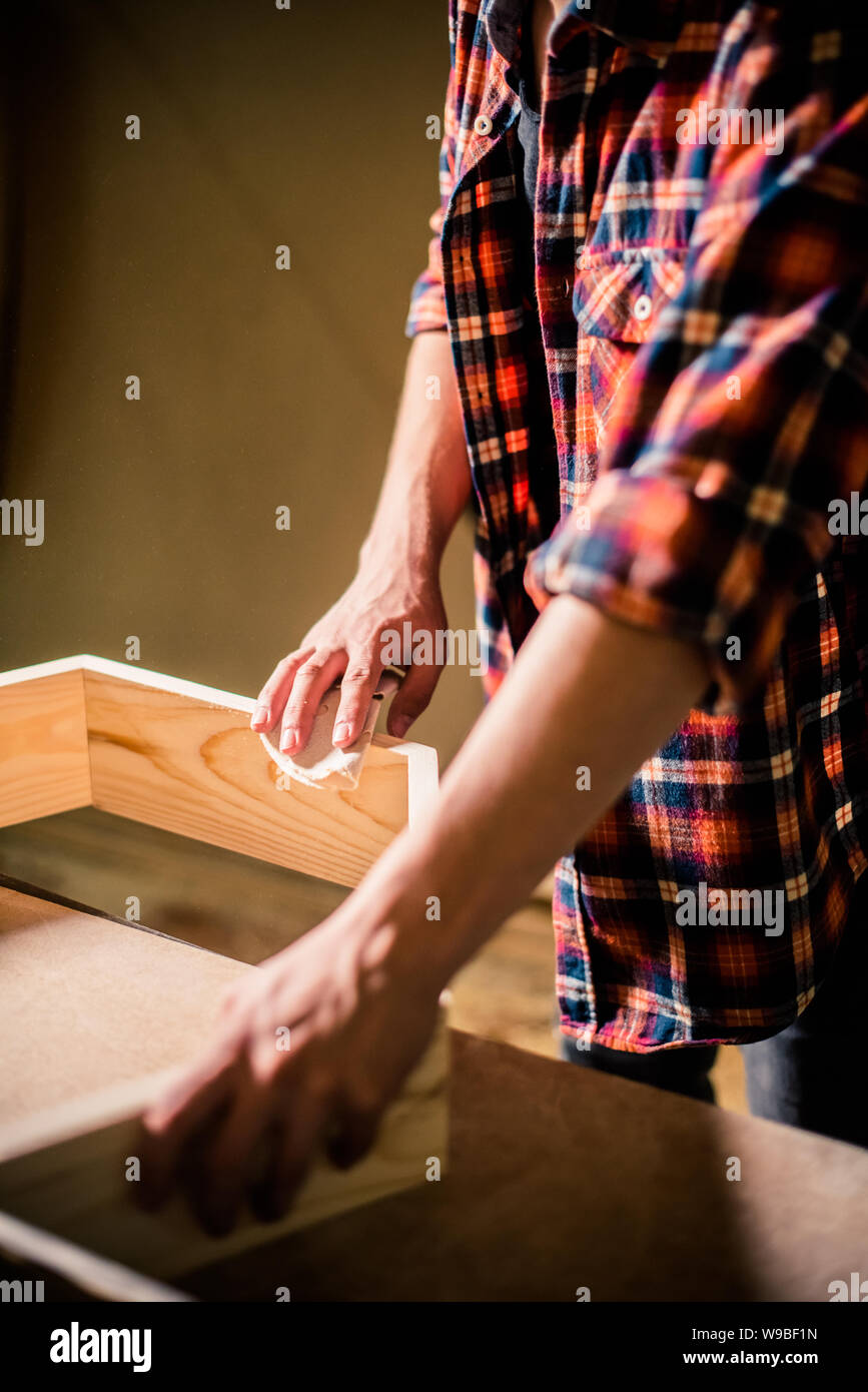Young handsome joiner working with wood in his carpentry workshop, woodworker business owner Stock Photo