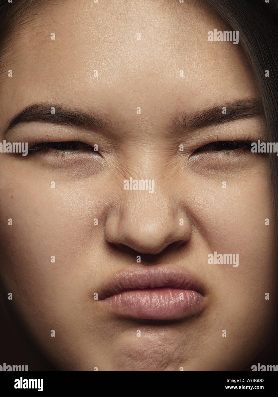 Close up portrait of young and emotional chinese woman. Highly detail photoshot of female model with well-kept skin and bright facial expression. Concept of human emotions. Angry, scaring. Stock Photo