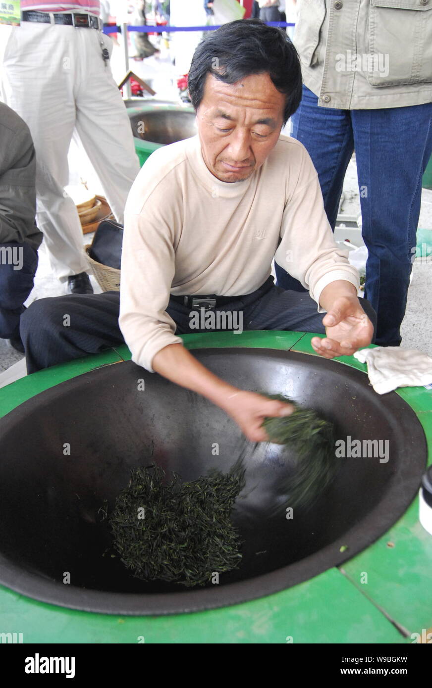 A Chinese man dries tea leaves in a wok in Qingdao city, east Chinas  Shandong Province, May 28, 2010. Worried gold has topped out? Do not trust  the Stock Photo - Alamy