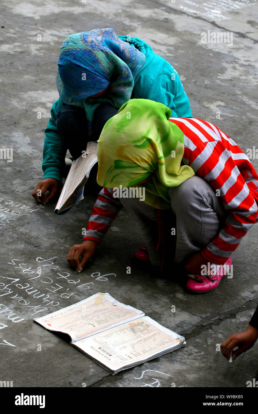 Hui ethnic students write down English words on the playground as they do not have enough paper and pen at the Heping Primary School in Linxia, northw Stock Photo