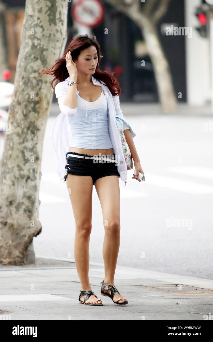 A trendy young Chinese woman walks on a street in the sweltering