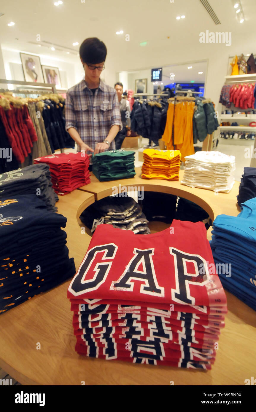 A Chinese staff piles up tee shirts in the GAP store at the Hong Kong Plaza  in Shanghai, China, 10 November 2010. U.S. clothing retailer Gap Inc ope  Stock Photo - Alamy